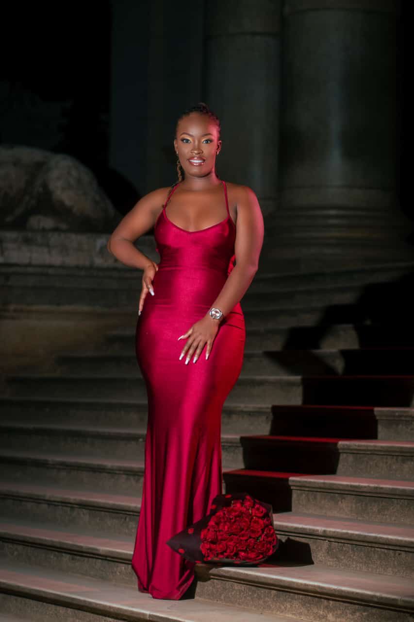 She's Confident bridal client in a red satin gown on stone steps with a bouquet of red roses, makeup by She's Confident