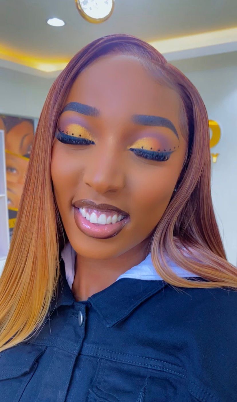 Soft glam selfie, warm honey straight wig with a side part, neutral peach eyeshadow and glossy mauve lip, smiling in golden interior light